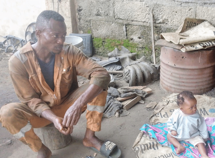 Nigerian mechanic spotted with 7-month-old baby at work after wife reportedly abandons them