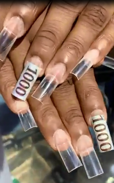 Outrage as lady cuts N1,000 notes to decorate her nails